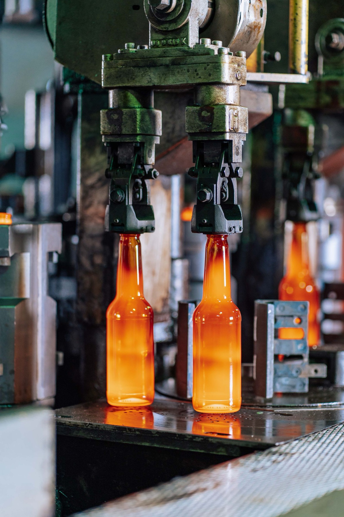 Close view of industrial glass bottle forming machinery.