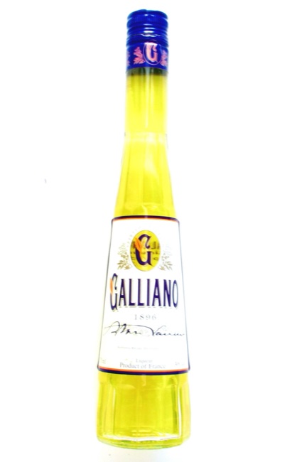 Extremely tall, narrow, faceted Galliano liqueur bottle filled with yellow liquid, with a blue cap and a widening lower body on a pale background.